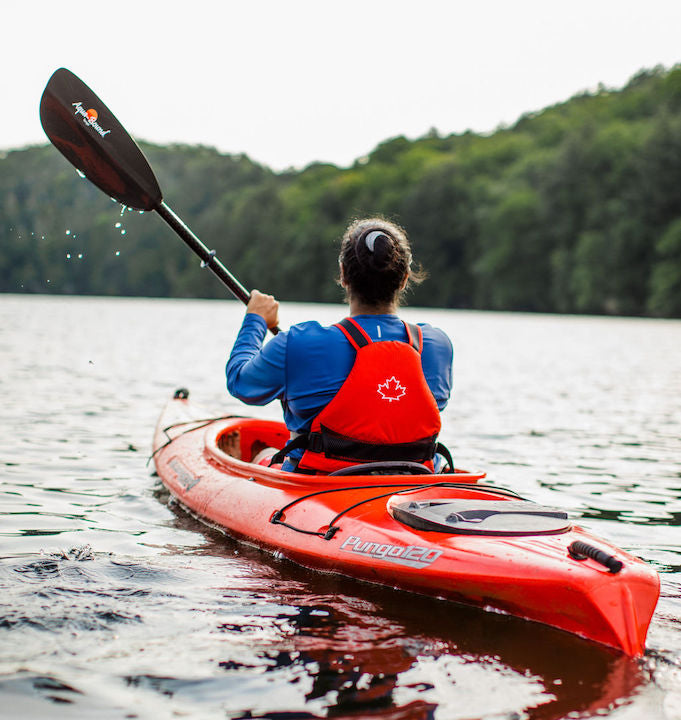 woman in a red kayak paddling on a lake