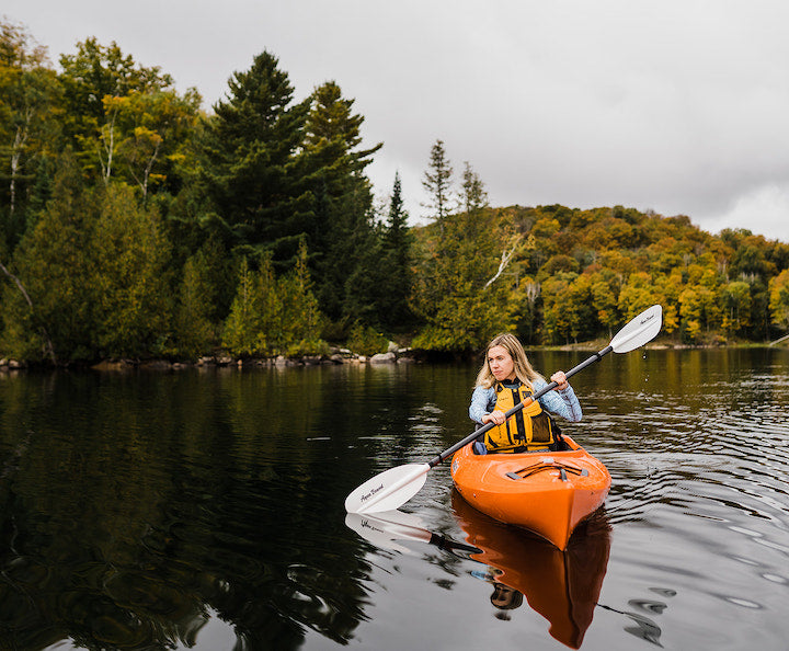 woman kayaks on a small calm lake