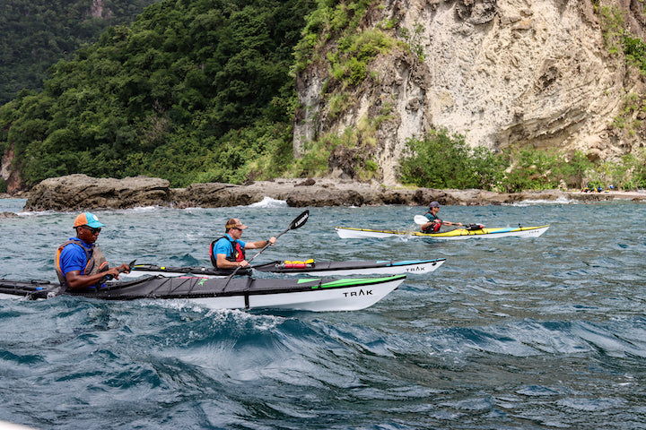 three sea kayakers along a rocky coast