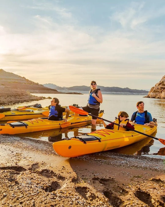 family on shore ready to kayak in a couple of tandem sit-in kayaks