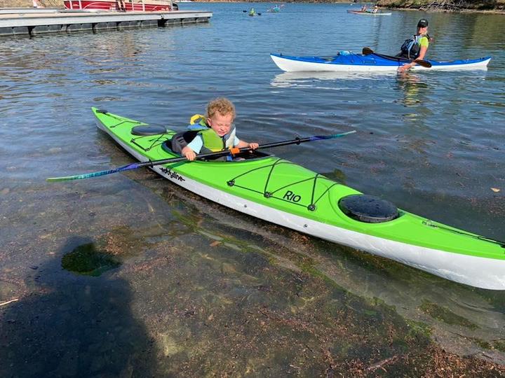 a very little child in an adult sized sit-in kayak