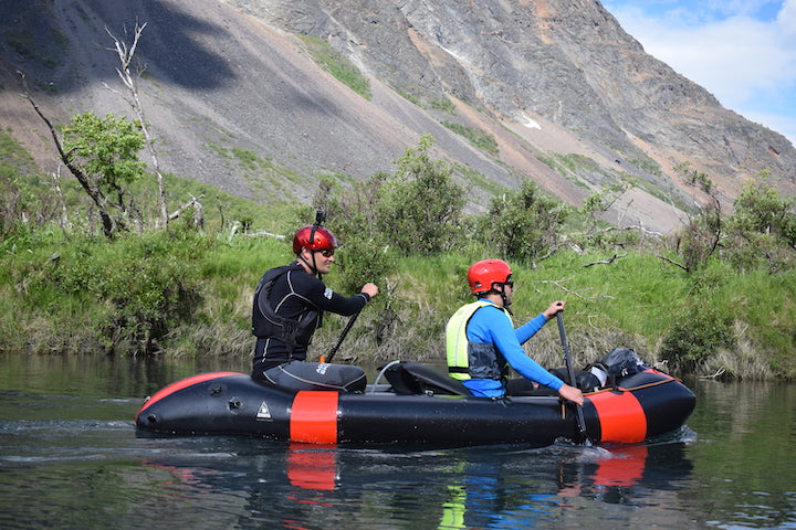 two men paddle a tandem packraft on a river