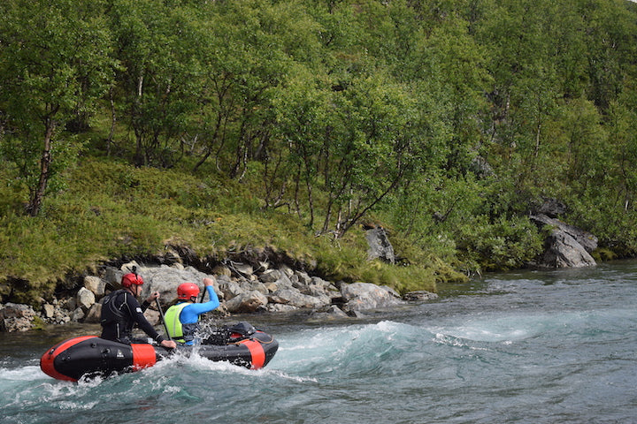 two men in a tandem packraft on a rapids section in the river