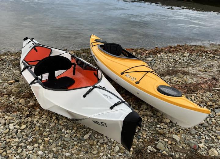 oru inlet folding kayak and eddyline sky10 hardshell kayak side by side on the beach
