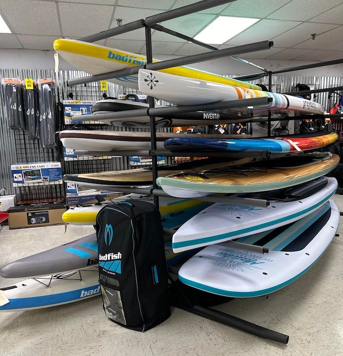 Paddleboards and kayaks on a rack inside Get Outdoors
