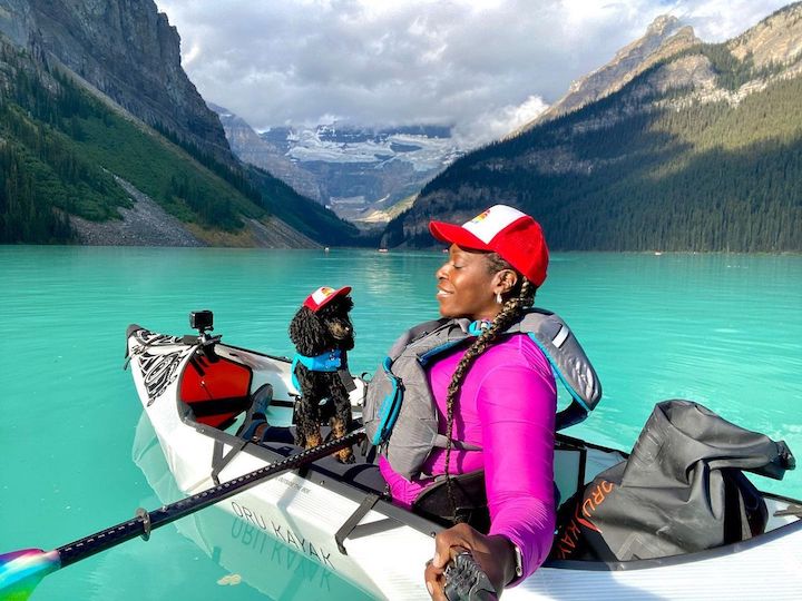 woman and her teeny dog in an Oru kayak on a mountain lake