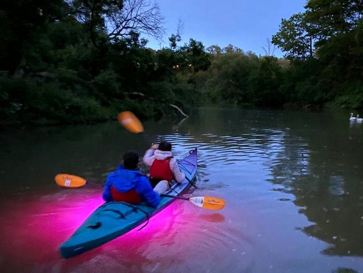 two people in a tandem kayak on a glow in the dark tour