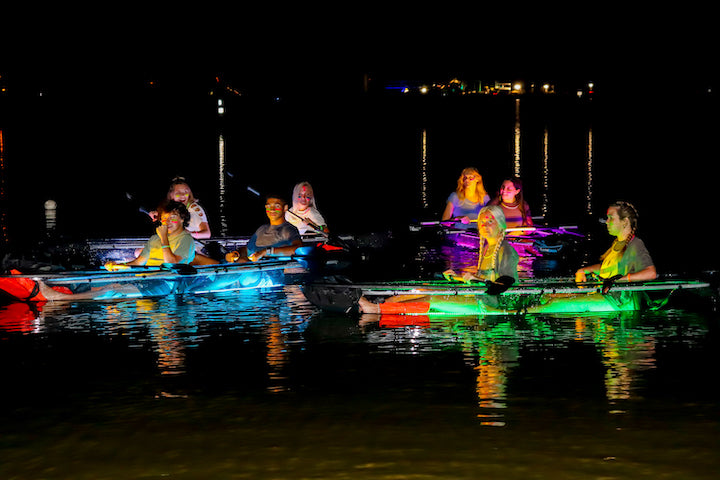 kayakers in glow-in-the-dark kayaks at night