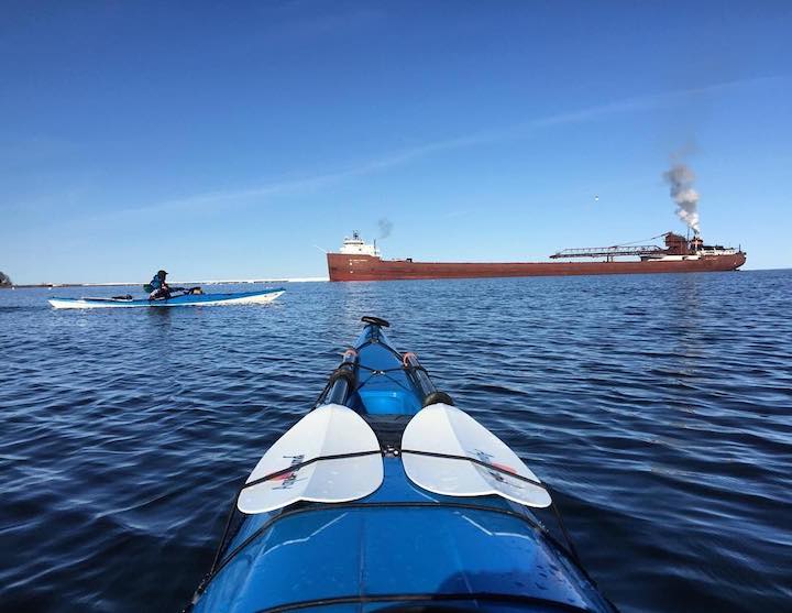 kayakers with iron ore ship