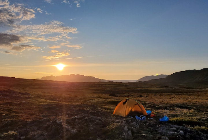 campsite with midnight sun on the horizon