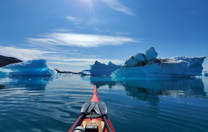kayakers view of paddling among Greenland's icebergs