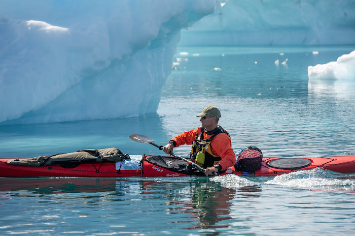 close up of a man kayaking among Greenland's icebergs