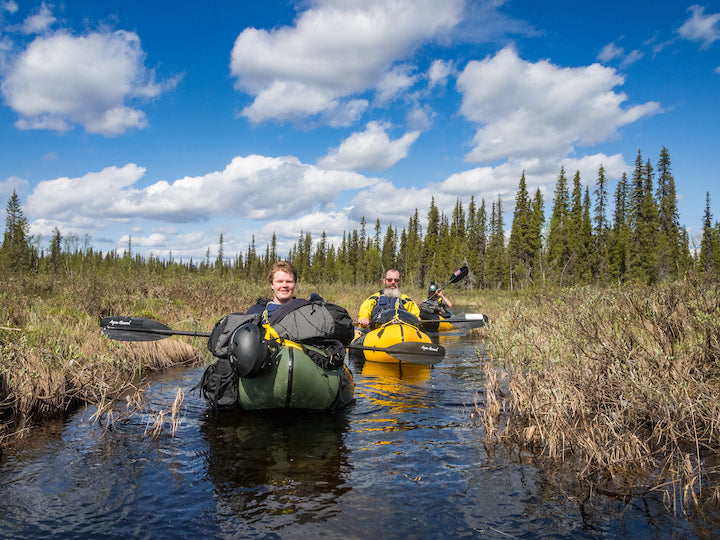 three packrafters on narrow river channel