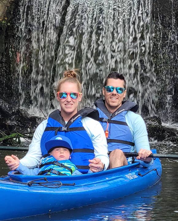 Dad, mom and baby in kayak in front of a waterfall