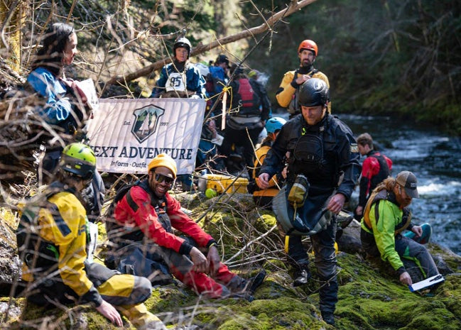 A group of whitewater kayakers on shore next to a river