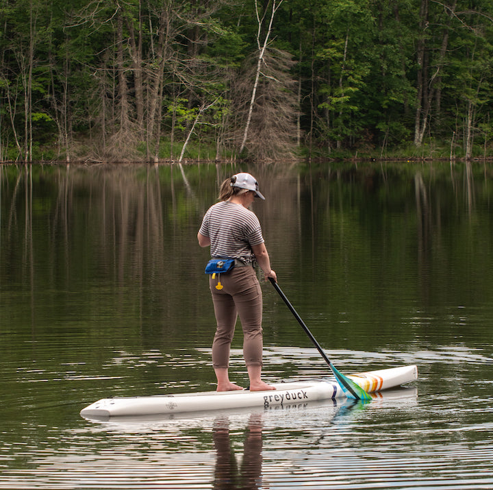 woman paddleboards wearing a hip pack inflatable PFD