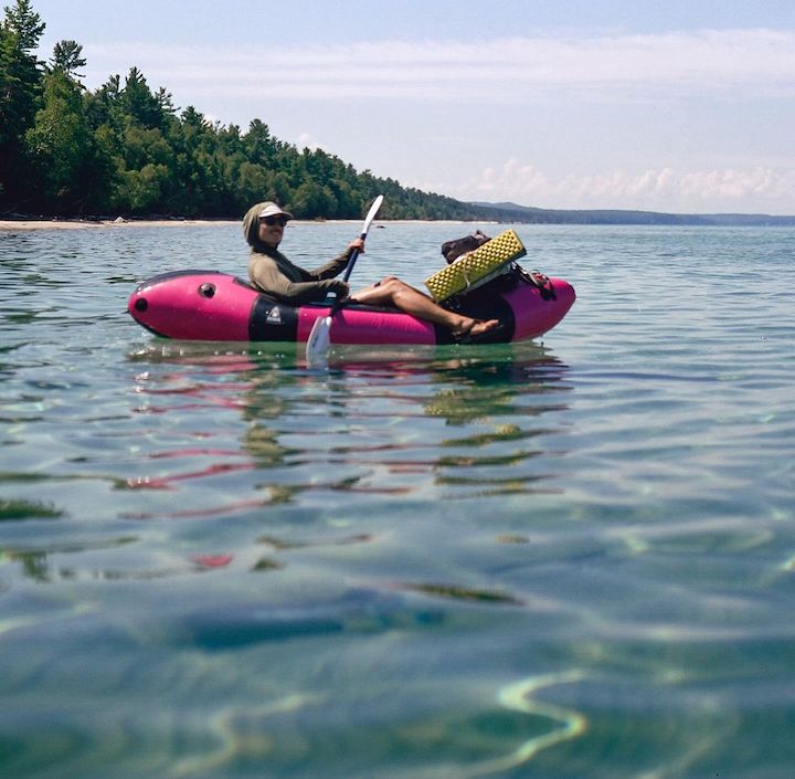 Owen in his loaded packraft on a mountain lake