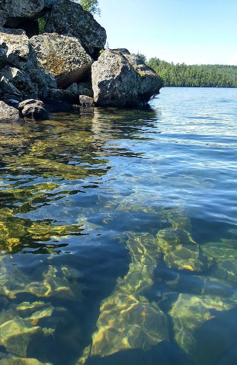 photo of a lake's shoreline with rocks above and below the water's surface