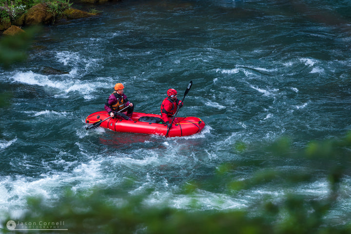 two paddlers in a tandem packraft on a river