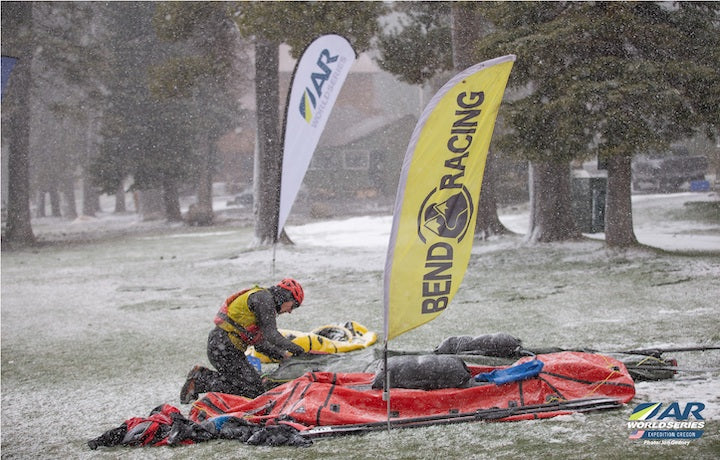 team member prepping packrafts for next race segment, in the snow