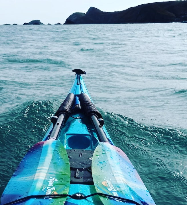 sea kayak bow with Aqua Bound paddles in the ocean near a UK island