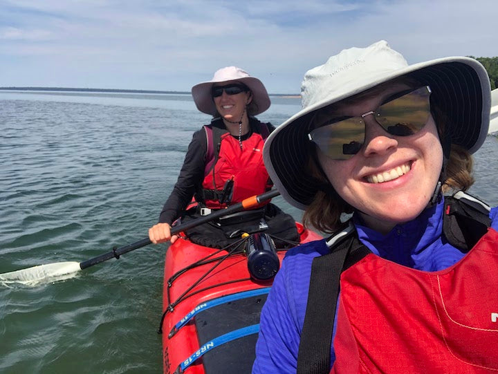 Rachel in the front of a tandem  kayak with another woman in the back, on Lake Superior