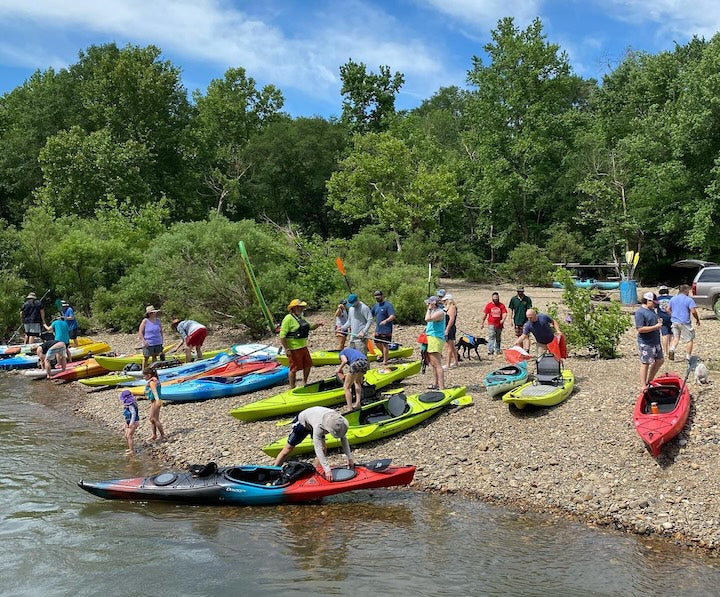 a bunch of people on the shore ready to kayak