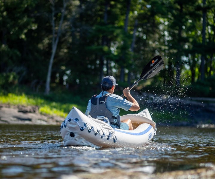 man paddles an inflatable kayak