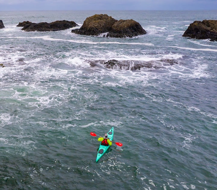 sea kayaker along a rocky, rough coast