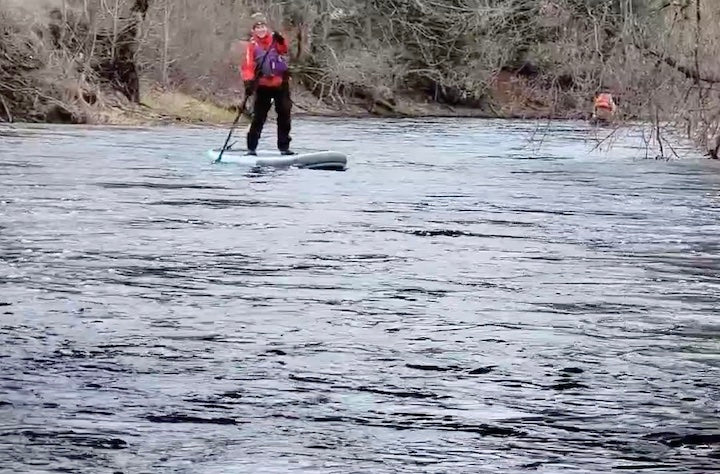 woman racing a SUP on a river in early spring