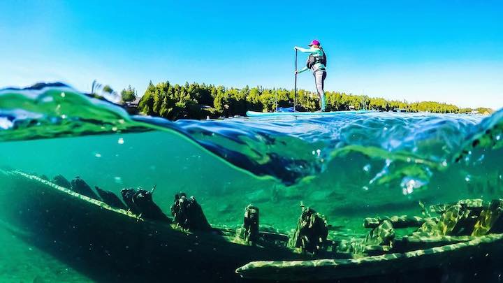 woman paddleboarding, photo taken at wave-height