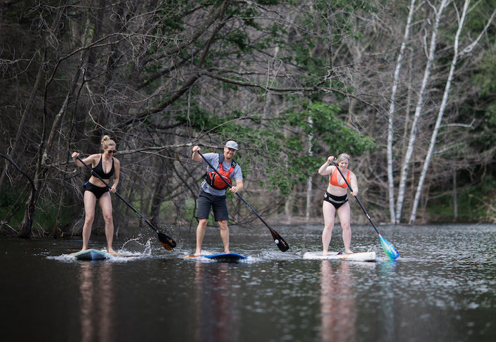 two women and a man paddleboarding together