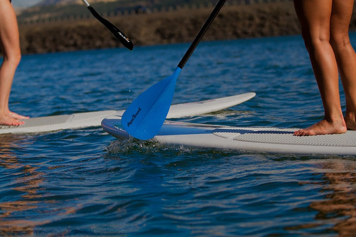 two paddlers on solid SUP boards, just the legs