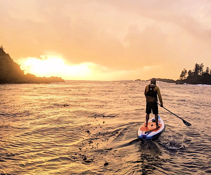 man paddleboarding at sunset in some waves