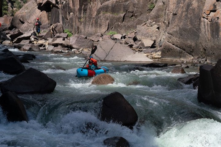 packrafter paddling down a rocky river in big rapids