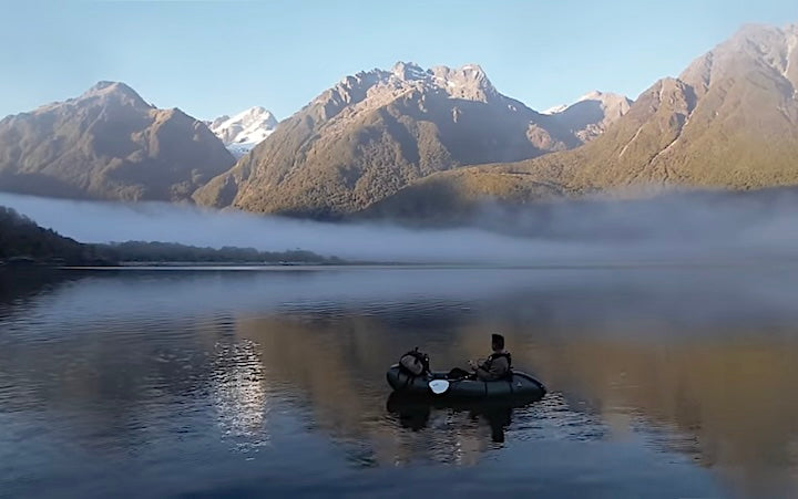Scott Williams packrafting a New Zealand lake, enjoying the mountain views