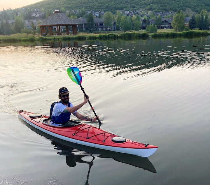 man kayaking in a red kayak on a calm lake