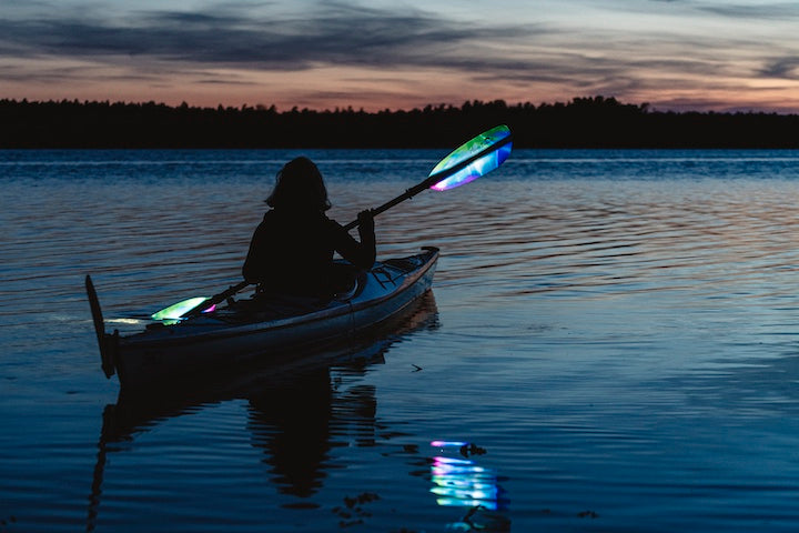 woman kayaking with an illuminated Tango at dusk