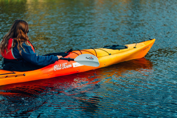 woman kayaking, bright orange kayak
