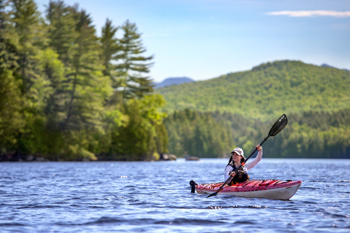 woman paddling a sit-inside kayak on a mountain lake