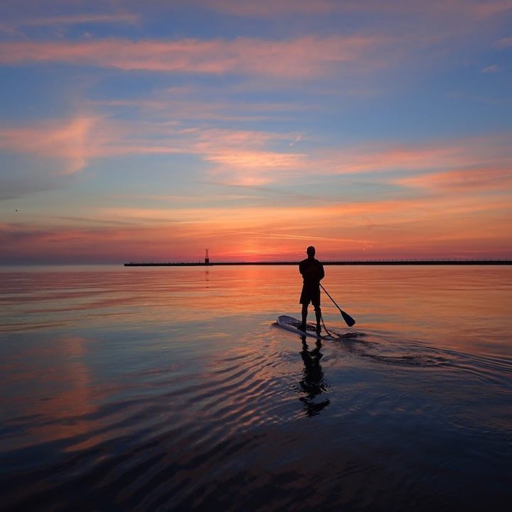 long shot of a paddle boarder at sunset