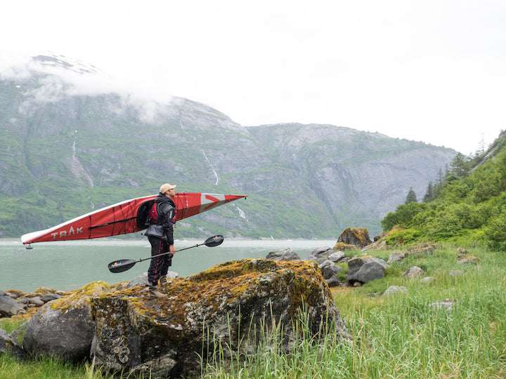 man with a folding kayak on shore