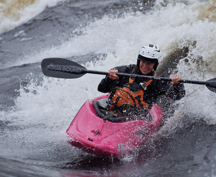 woman in a whitewater kayak on a big wave using Aqua Bound's Aerial whitewater kayak paddle