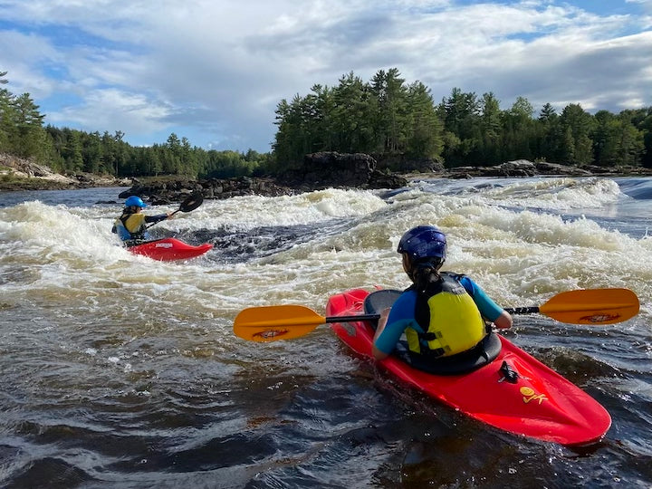 two whitewater kayakers in river rapids