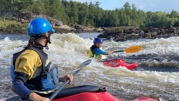 two whitewater kayakers in river rapids