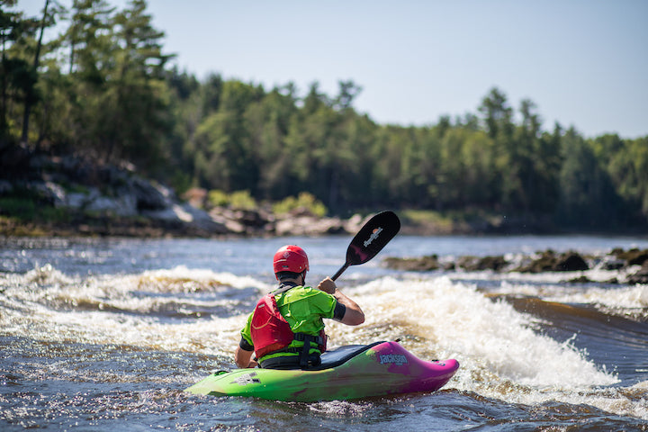 man whitewater kayaking in some larger rapids