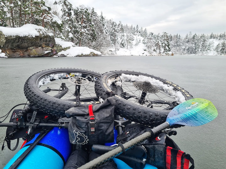 bikerafter with bike strapped onto packraft, on a lake in winter