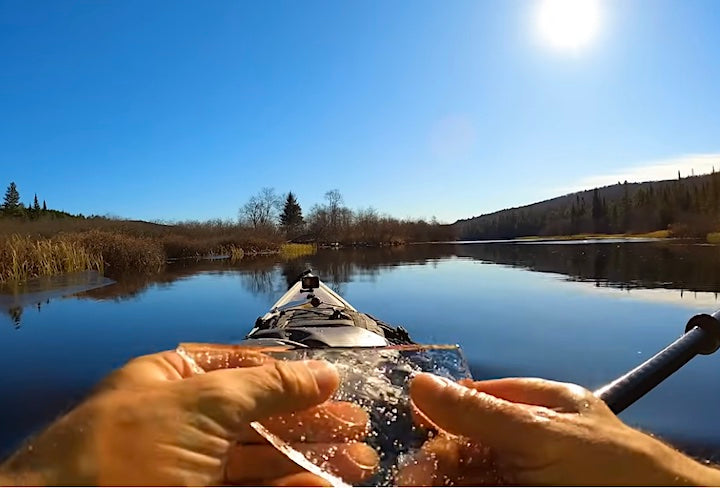 kayaker on a calm lake on a sunny day holdling lake ice