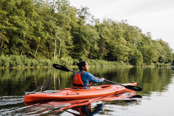 woman kayaking on a lake in a red kayak