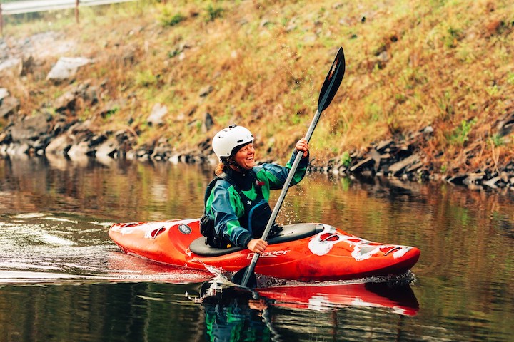 woman laughing in a red whitewater kayak on the river